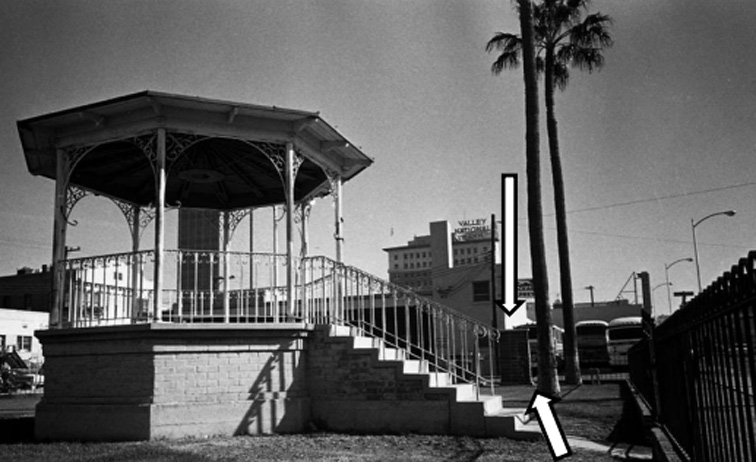 A vintage snapshot of a park with a gazebo. Two arrows designate the position of the marker near an iron fence.