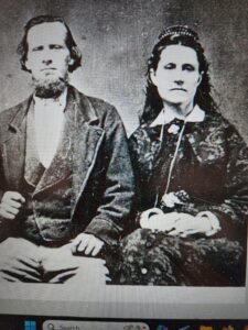 A black and white photo from 1865 with Ebenezer sitting on the left next to his wife, Mary Ann Bryce with period clothing and jewelry.